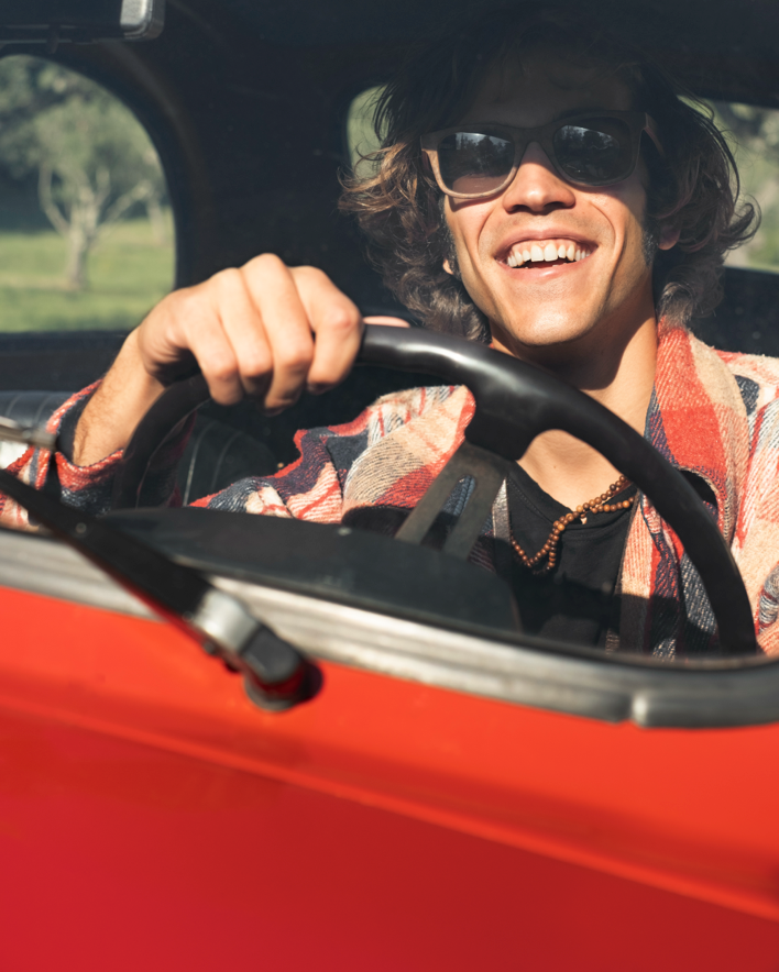 imagen de un chico sonriente conduciendo un coche de alquiler rojo para el apartado de dudas del servicio de alquiler de vehiculos de alvemacorent